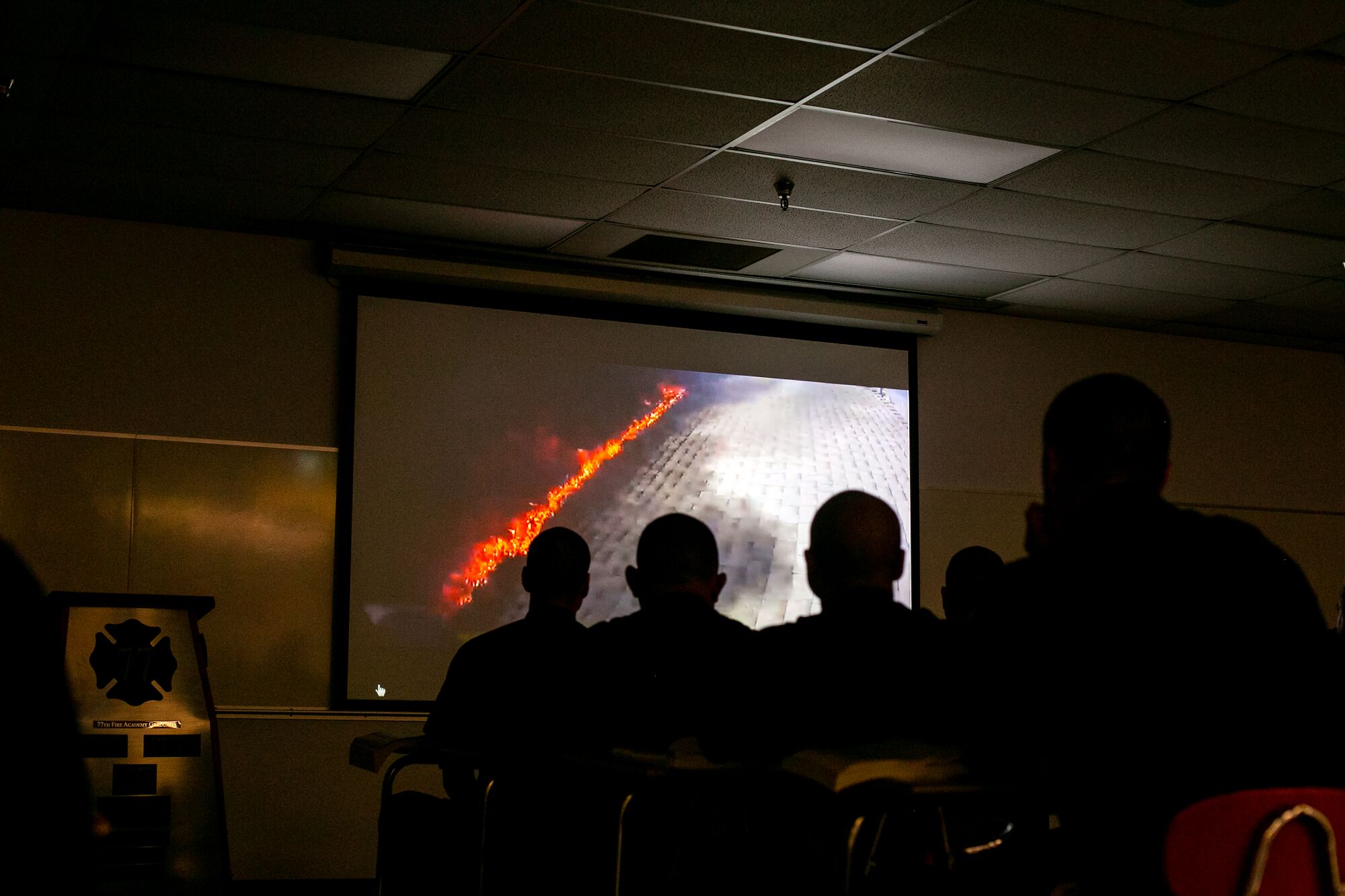 Recruits watch a video in March that shows other firefighters cutting a ventilation hole on the roof of a home during a structure fire.