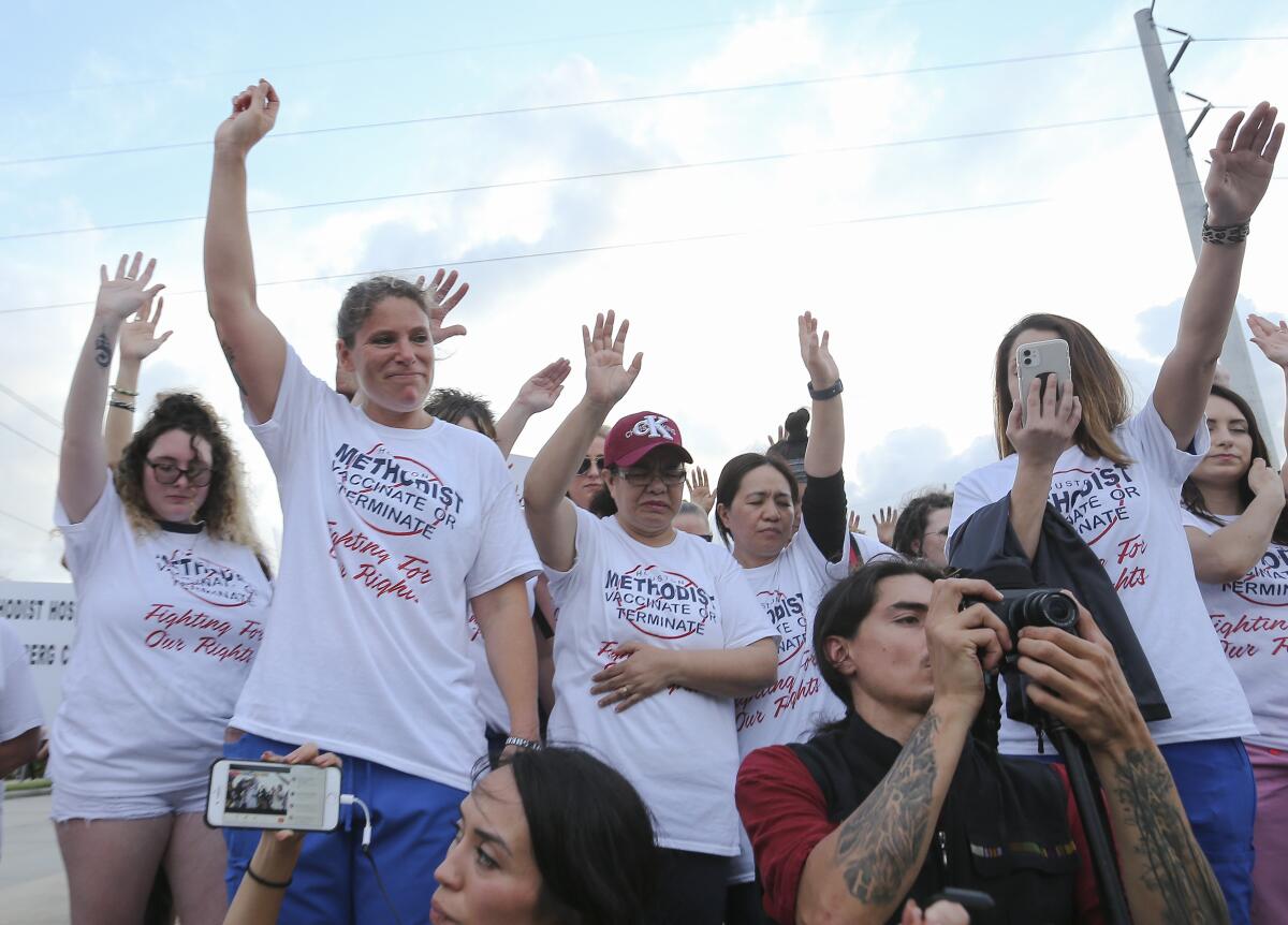 A group wears matching T-shirts with a red circle and slash mark through the words, "Methodist Vaccinate or Terminate" 