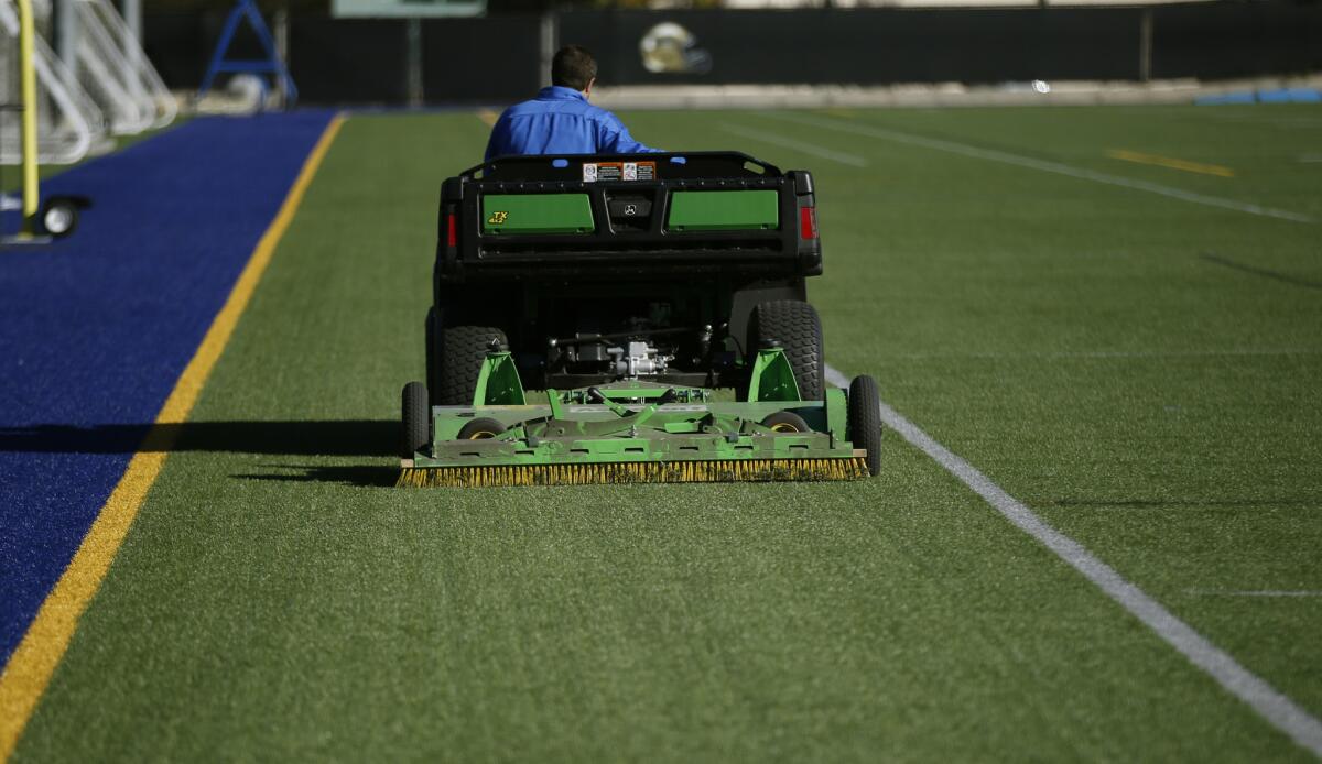 Kyle Urban, competitive sports coordinator for UCLA's recreation program, grooms the artificial turf at the campus' intramural field.