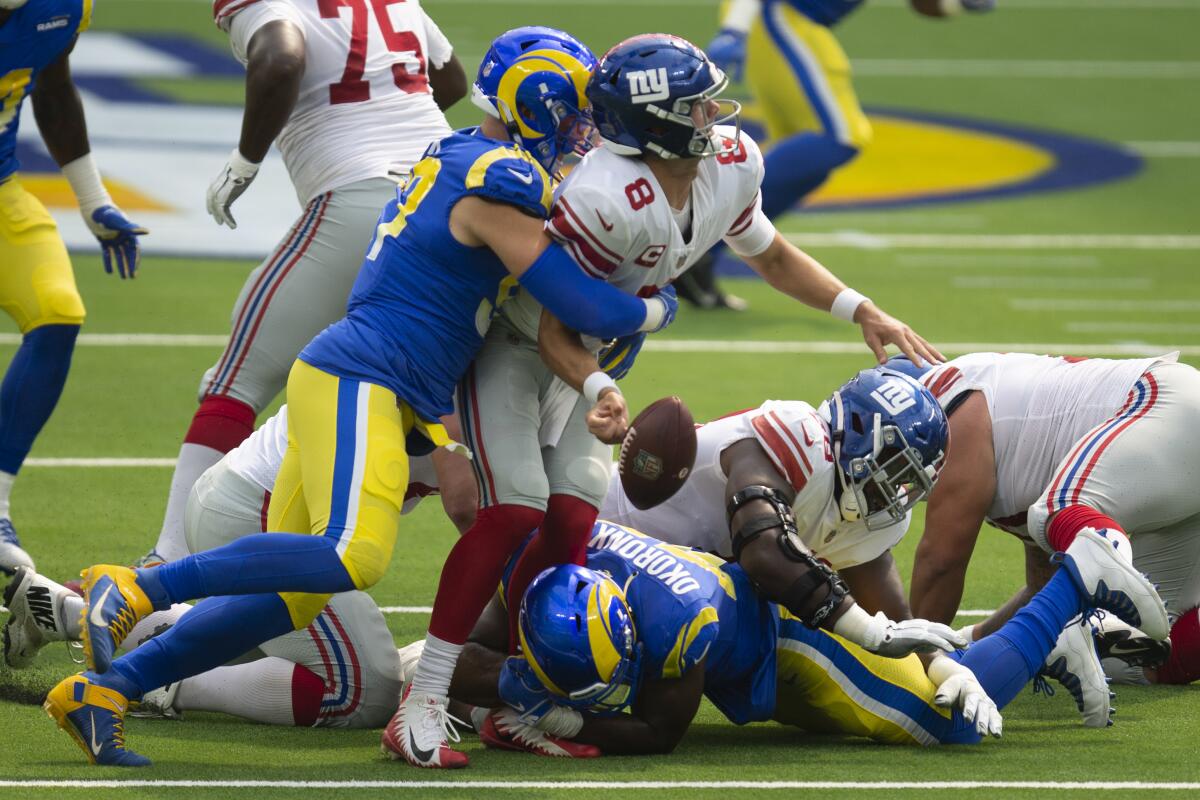 Rams defensive end Morgan Fox, left, and linebacker Obo Okoronkwo cause New York Giants quarterback Daniel Jones to fumble.