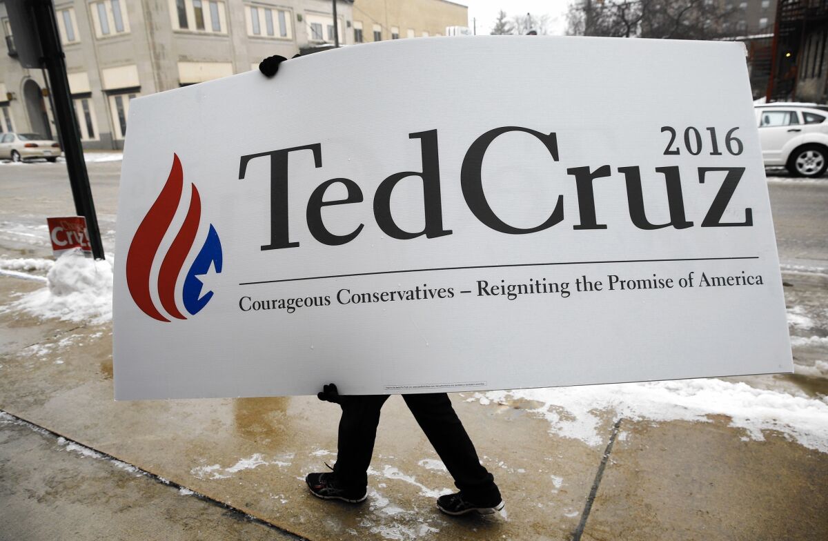 In Mason City, an Iowan carries a campaign sign into a town hall meeting on Jan. 8 hosted by Sen. Ted Cruz.