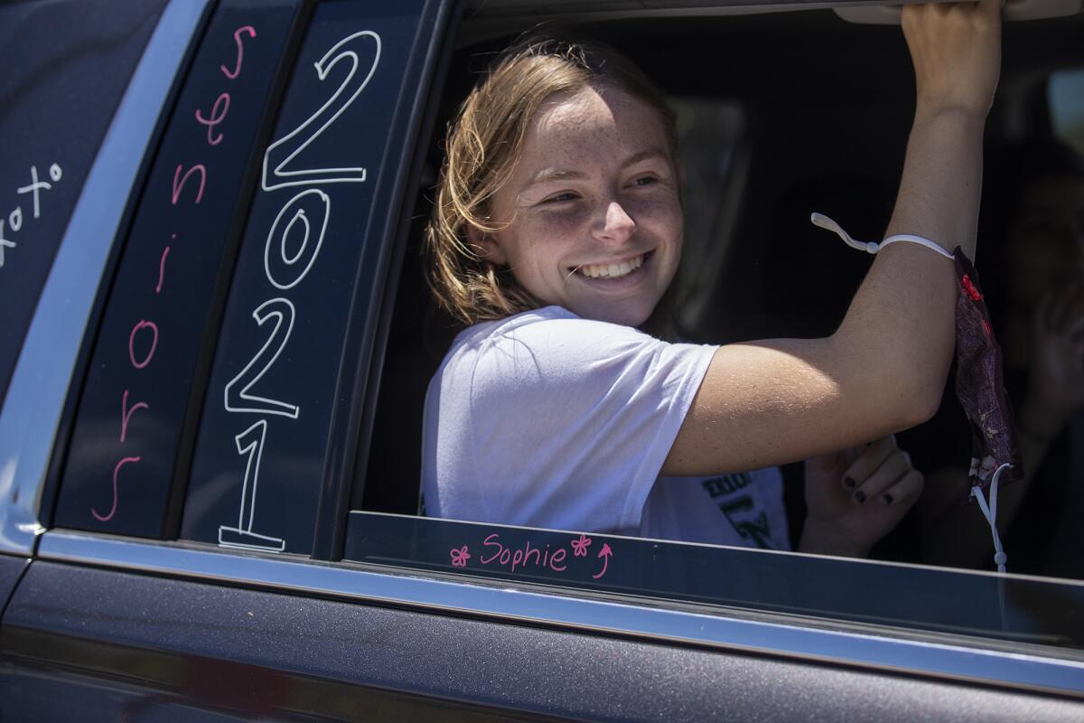 A Costa Mesa student smiles from inside a car as it passes by Estancia High School June 9.