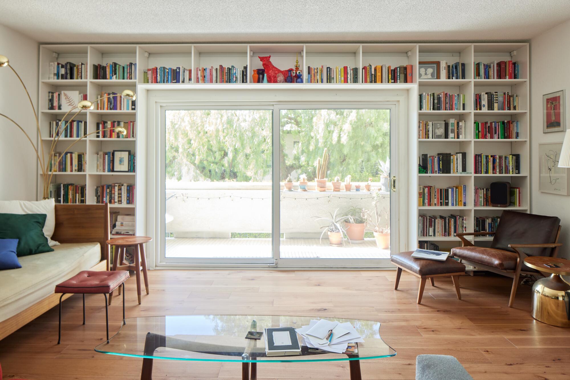 An image of a living room, a white book case framing the glass doors that go out to a patio.