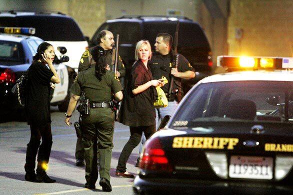 Orange County sheriff's deputies escort shoppers to their vehicles after a suspect in a jewelry store robbery was killed in the parking structure of The Shops at Mission Viejo.