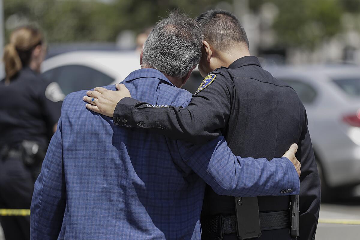 CSU Fullerton President Framroze Virjee, left, embraces University Police Chief Raymond Aguirre after a news conference reporting the arrest of Chuyen Vo, 51, who is suspected of killing Steven Shek Keung Chan, 57, at Cal State Fullerton on Monday.