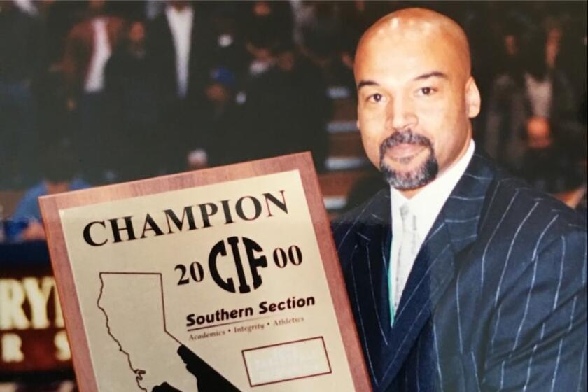 Coach Michael Lynch holds up a CIF Southern Section championship plaque.