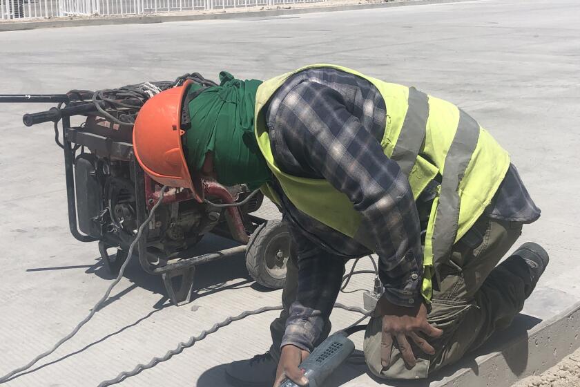 Gerson Paredes, 20, works a machine he calls a waafer to smooth out the edge of a curb at a factory being built on the southeastern outskirts of Tijuana. Paredes arrived in Tijuana in November 2018 with a large caravan of Central Americans.