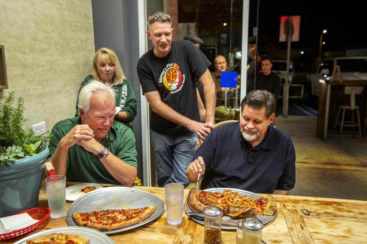 Huntington Beach Mayor Erik Petersen tries to eat an entire 6-pound calzone in 30 minutes Sunday as Stoney's Pizza owner Brandt Stebbins, center, watches with Bob and Linda Wentzel.