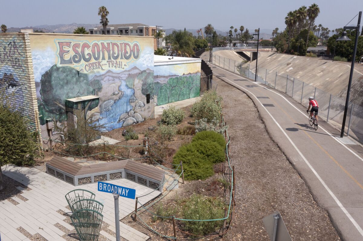 A bike rider heads east on Escondido Creek Trail bike path passes by the pocket park with its pollinator garden on Broadway