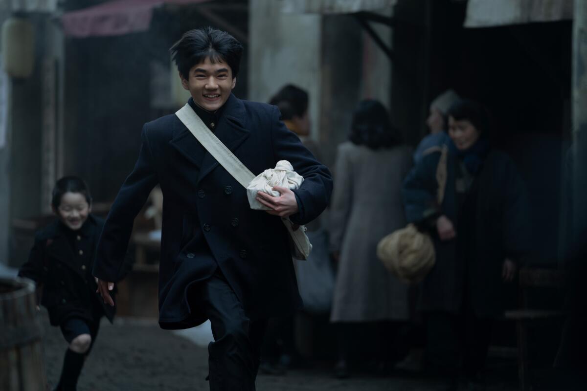 Two boys in dark clothing running through an alleyway.