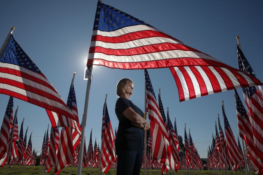 Covina, CA - November 12: Linda Logan, who started Field of Valor to help veterans eleven years ago, stands among fluttering flags installation on the grounds of Sierra Vista Middle School on Saturday, Nov. 12, 2022 in Covina, CA. (Irfan Khan / Los Angeles Times)