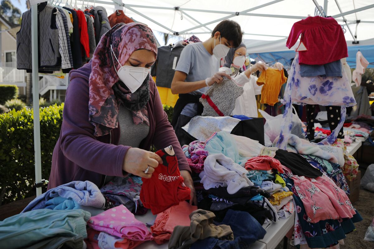 Zulfar Shaker, left,  from the San Diego Afghan Refugees Aid Group sort through clothes during a distribution event