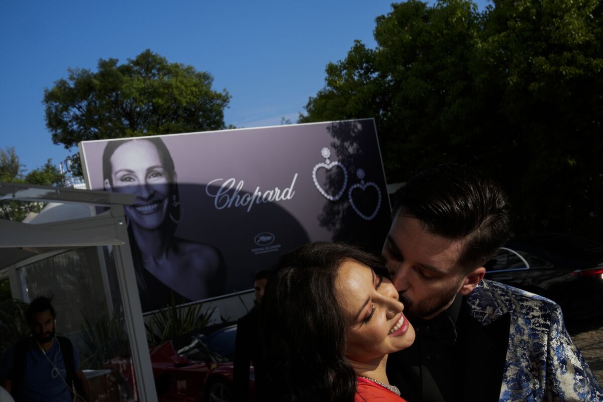 In this May 22, 2023 photo, festivalgoers kiss at the entrance to the Martinez Hotel before a premiere during the 76th edition of the Cannes Film Festival in Cannes, southern France. (AP Photo/Daniel Cole)