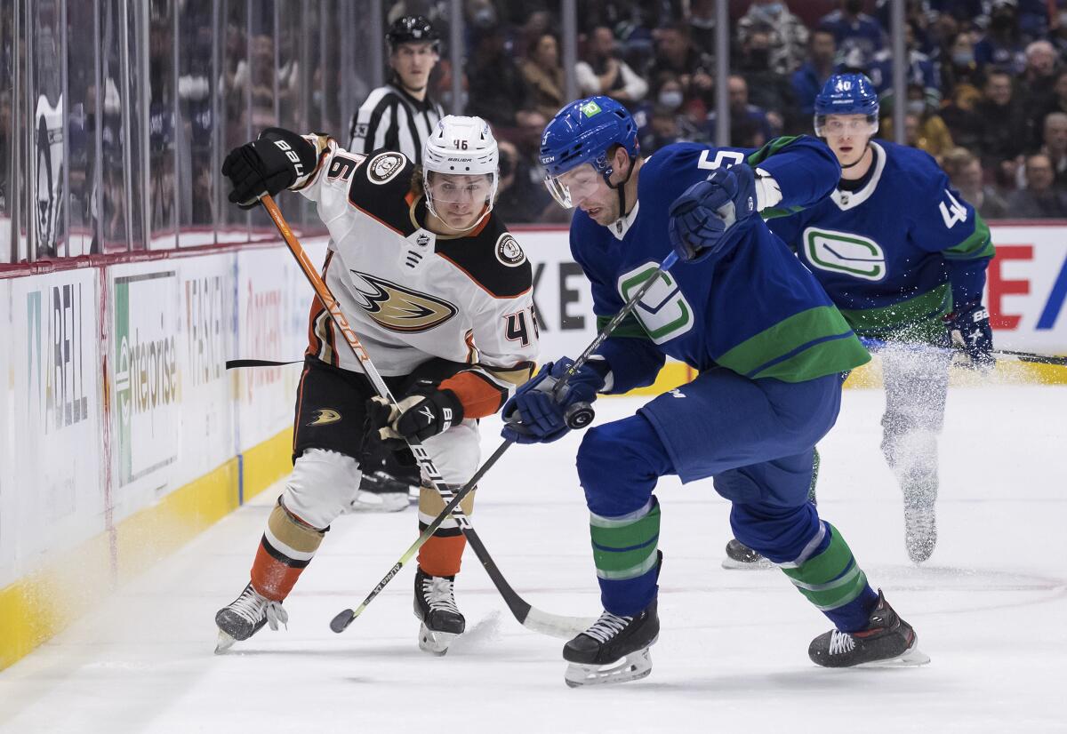 Anaheim Ducks' Trevor Zegras (46) and Vancouver Canucks' Tucker Poolman (5) vie for the puck during the first period of an NHL hockey game Tuesday, Nov. 9, 2021, in Vancouver, British Columbia. (Darryl Dyck/The Canadian Press via AP)