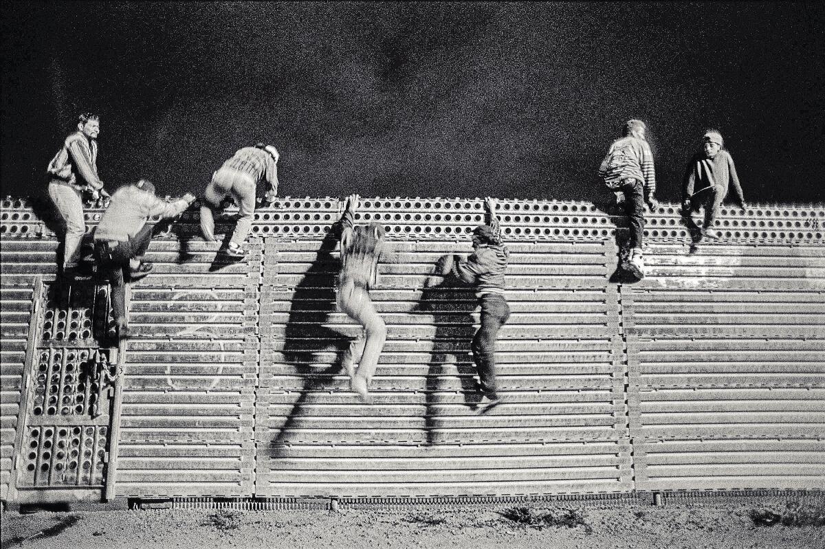 A pair of young men free fall down the north side of the U.S.-Mexico border fence on June 18, 1992, before the implementation of Operation Gatekeeper.