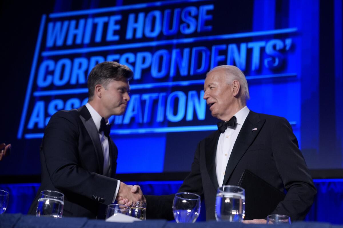 Colin Jost and President Biden shake hands on stage