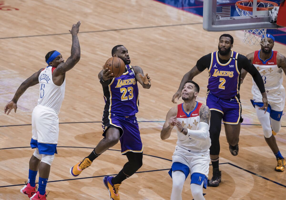 Los Angeles Lakers forward LeBron James (23) shoots as New Orleans Pelicans guard Eric Bledsoe (5) and center Willy Hernangomez (9) defend in the first quarter of an NBA basketball game in New Orleans, Sunday, May 16, 2021. (AP Photo/Derick Hingle)