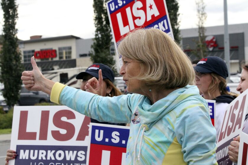 U.S. Sen. Lisa Murkowski, an Alaska Republican, flashes a thumbs-up to a passing motorist while waving signs, Tuesday, Aug. 16, 2022, in Anchorage, Alaska. Murkowski faces 18 challengers in the state's open primary for U.S. Senate, in which the top four vote-getters regardless of party affiliation will advance to the November general election. (AP Photo/Mark Thiessen)