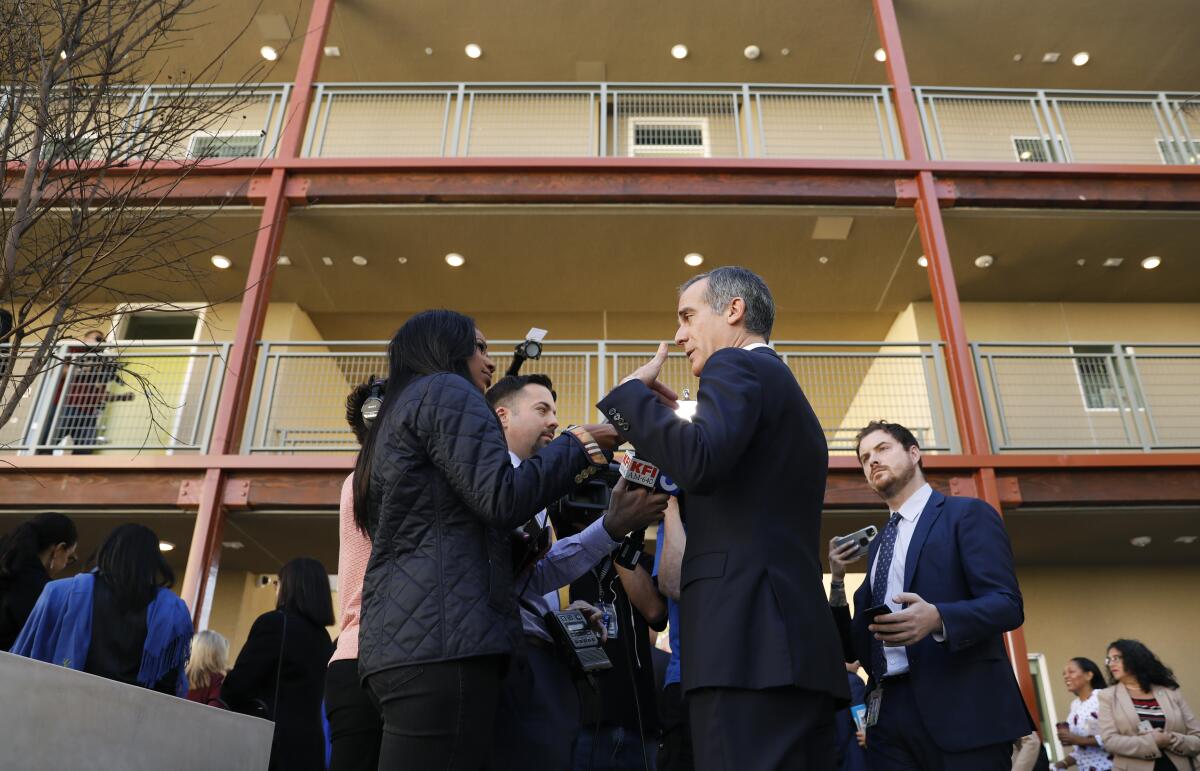 A group of reporters interview L.A. Mayor Eric Garcetti at a supportive housing project in South Los Angeles.
