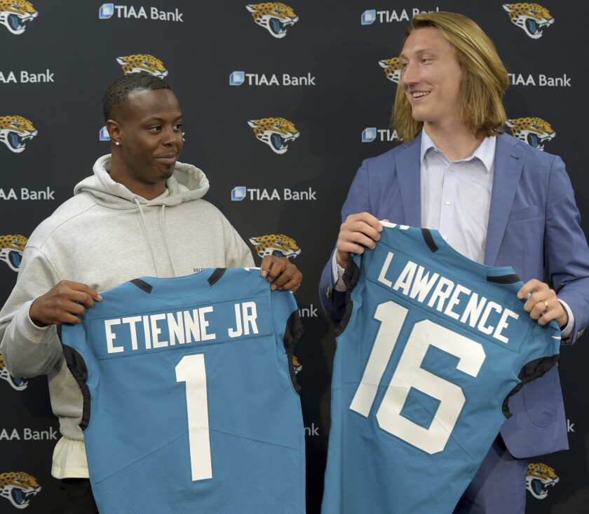 FILE - Former Clemson teammates Travis Etienne and Trevor Lawrence pose with their Jacksonville Jaguars jerseys during an introductory press conference in Jacksonville, Fla., in this Friday, April 30, 2021, file photo. (Bob Self/The Florida Times-Union via AP, File)