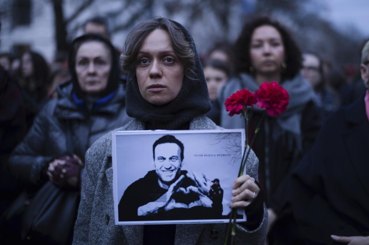 Una mujer sostiene flores y un retrato del destacado opositor ruso Alexei Navalny 
