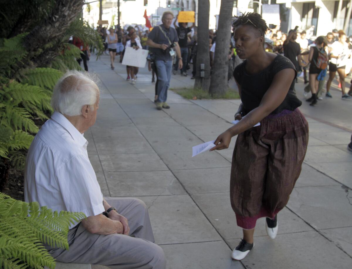 Protester Patrisse Cullors-Brignac hands a leaflet to a man on the sidewalk during a rally last week in Beverly Hills calling for an end to racial profiling in the wake of the George Zimmerman verdict.