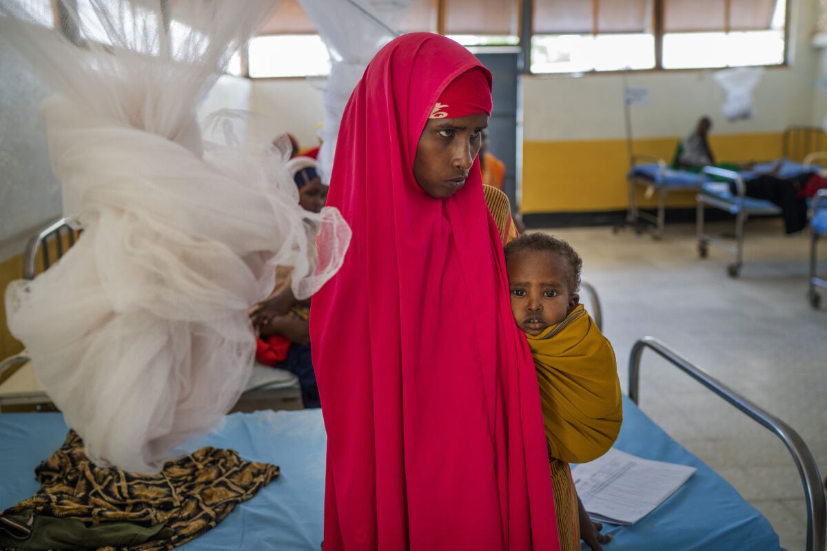 A woman holds a child at a clinic in Dollow, Somalia, on Wednesday, Sept. 21, 2022. Somalia is in the midst of the worst drought anyone there can remember. A rare famine declaration could be made within weeks. Climate change and fallout from the war in Ukraine are in part to blame. (AP Photo/Jerome Delay)
