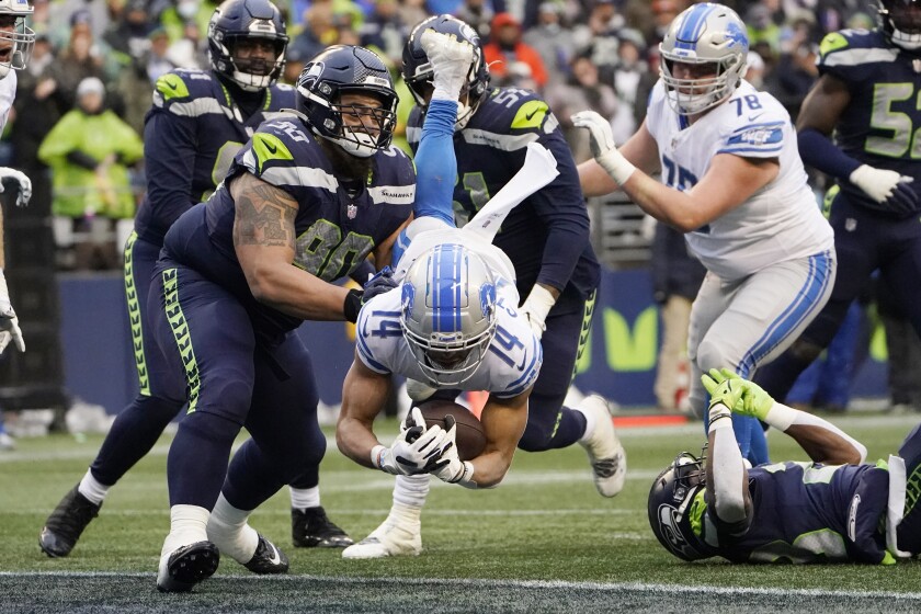 Detroit Lions Amon-Ra St. Brown comes down in front of Seattle Seahawks defensive tackle Bryan Mone (90) with a reception for a two-point conversion during the second half of an NFL football game, Sunday, Jan. 2, 2022, in Seattle. (AP Photo/Elaine Thompson)