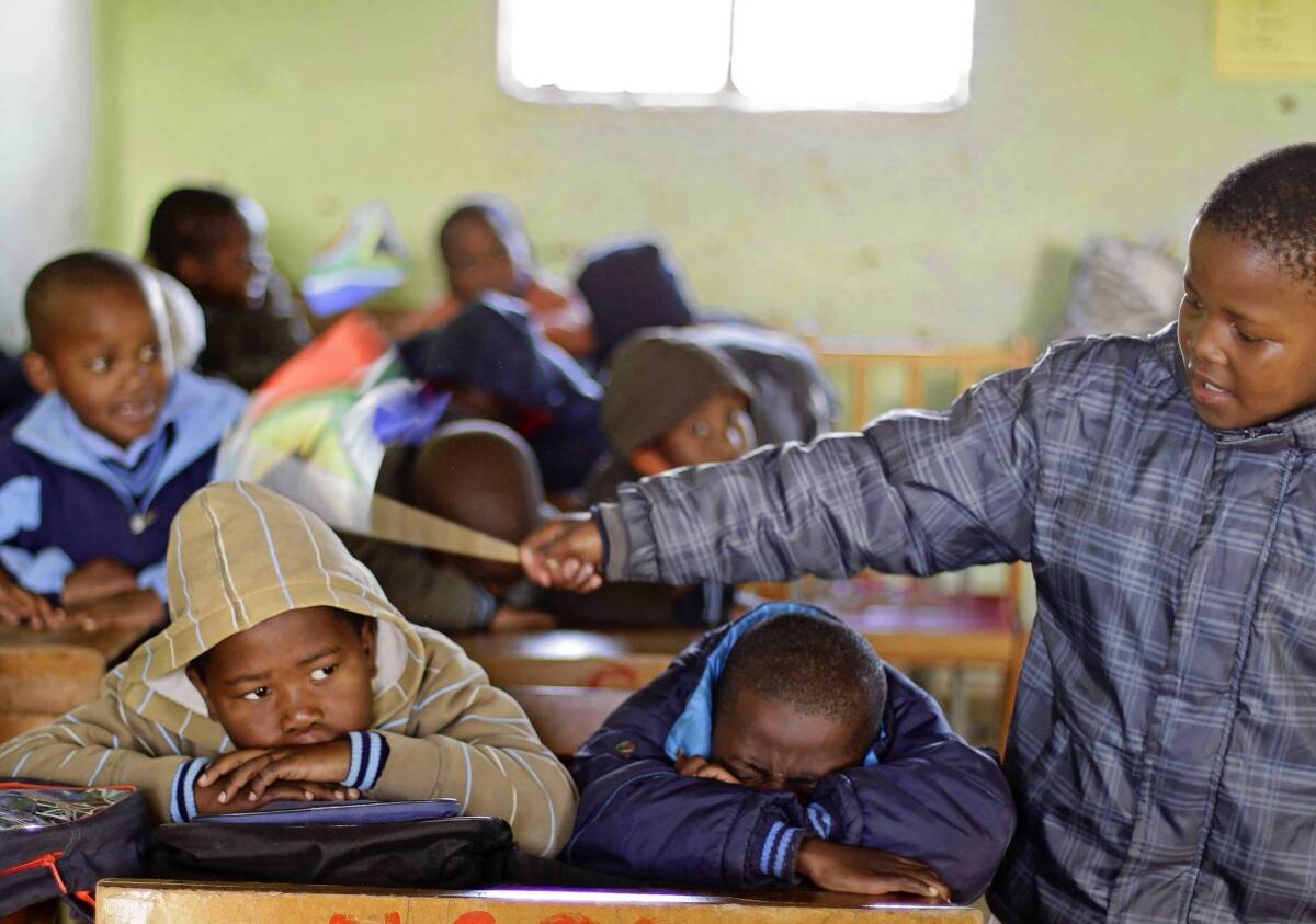 A boy keeps control over fellow students by tapping them with a South African flag at a school in Qunu.