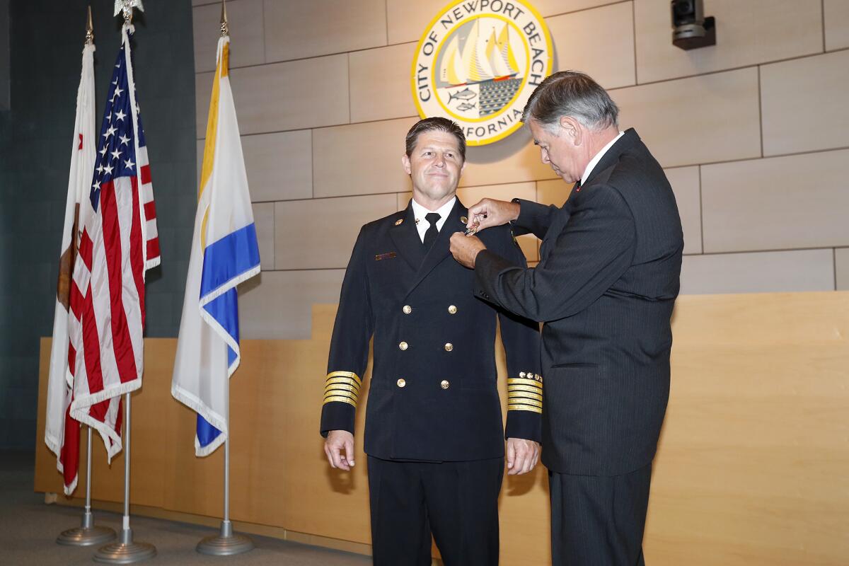 Newport Beach Fire Chief Jeff Boyles is pinned with his new badge by his father, Gary, a retired fire chief, during a ceremony at City Hall on Wednesday.