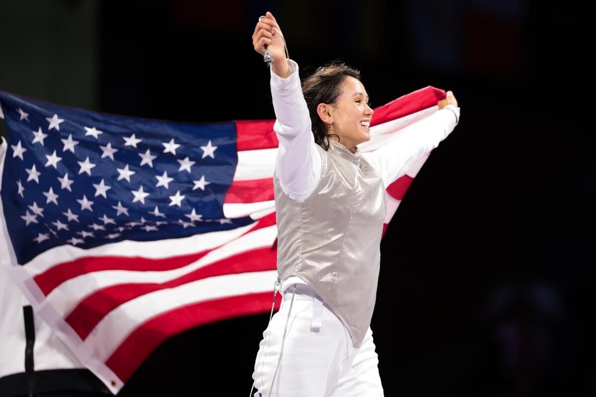 Lee Kiefer waves the American flag and celebrates after winning gold in an all U.S. women's fencing foil final 