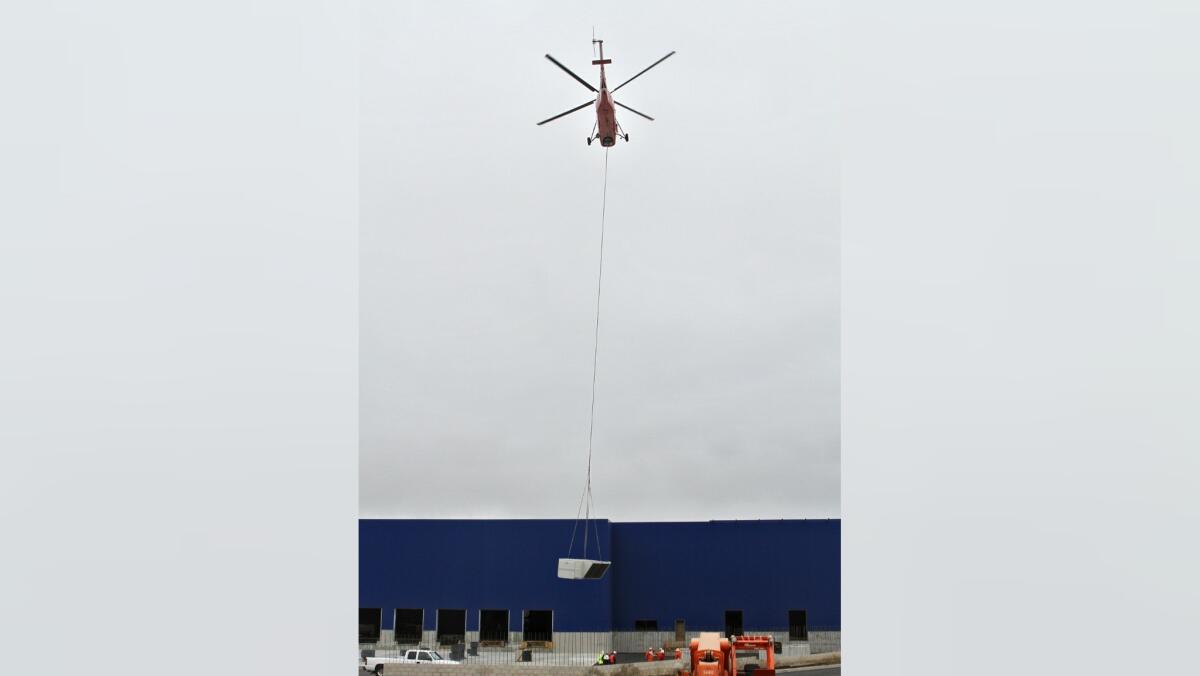 A helicopter lifts an air conditioning unit to the roof of the new IKEA building in Burbank on Saturday, June 11, 2016.
