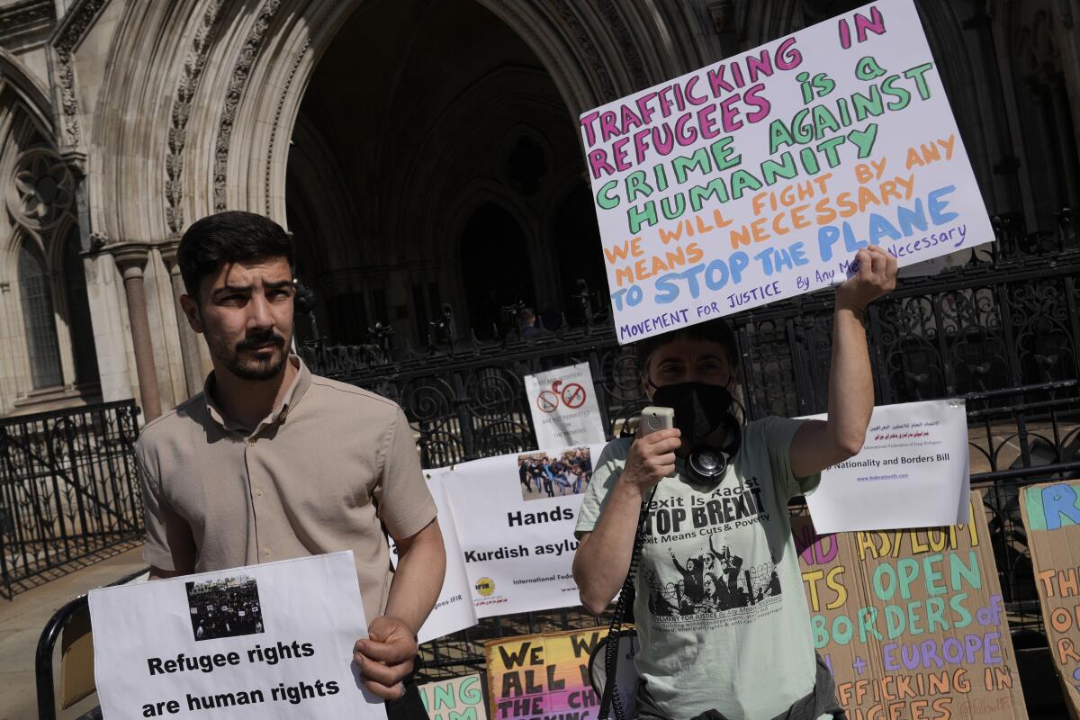 Protesters stand outside the High Court where the ruling on Rwanda deportation flights is taking place, in London Monday, June 13, 2022. Opponents of the British government’s plan to deport migrants to Rwanda prepared for an appeals court hearing Monday amid the political backlash following reports that Prince Charles had privately described the policy as “appalling.” (AP Photo/Alastair Grant)