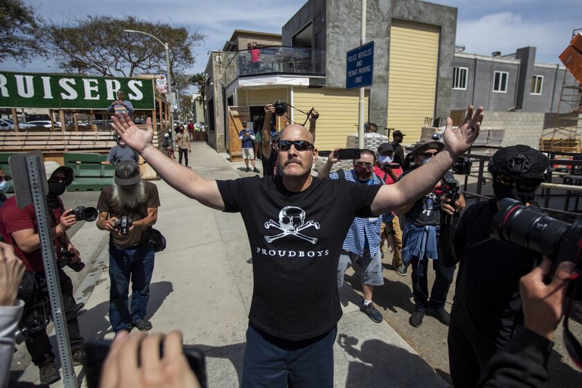A man wears a Proudboys shirt as a crows surronds him in Huntington Beach on Sunday, April 11.