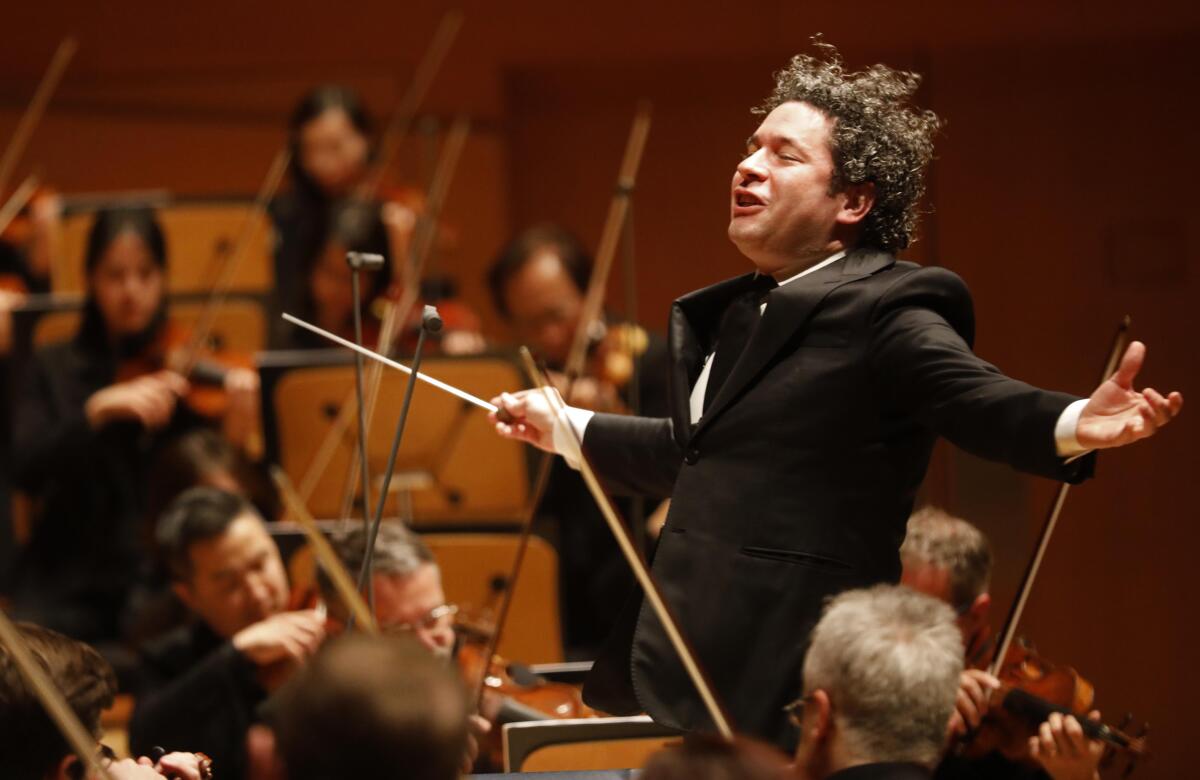 An exuberant Gustavo Dudamel conducts inside a concert hall.