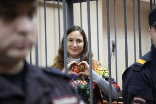 Sasha Skochilenko, a 33 year-old artist and musician shows a heart behind bars in the court room as she waits for a hearing in the Vasileostrovsky district court in St. Petersburg, Russia, Monday, Nov. 13, 2023. A court in St Petersburg has to deliver a verdict to a young artist Sasha Skochilenko on charges of spreading "fakes" about the Russian military after she replaced four small price tags in a St. Petersburg supermarket with anti-war slogans. The prosecution asked to sentence her to 8 years in prison. (AP Photo/Dmitri Lovetsky)