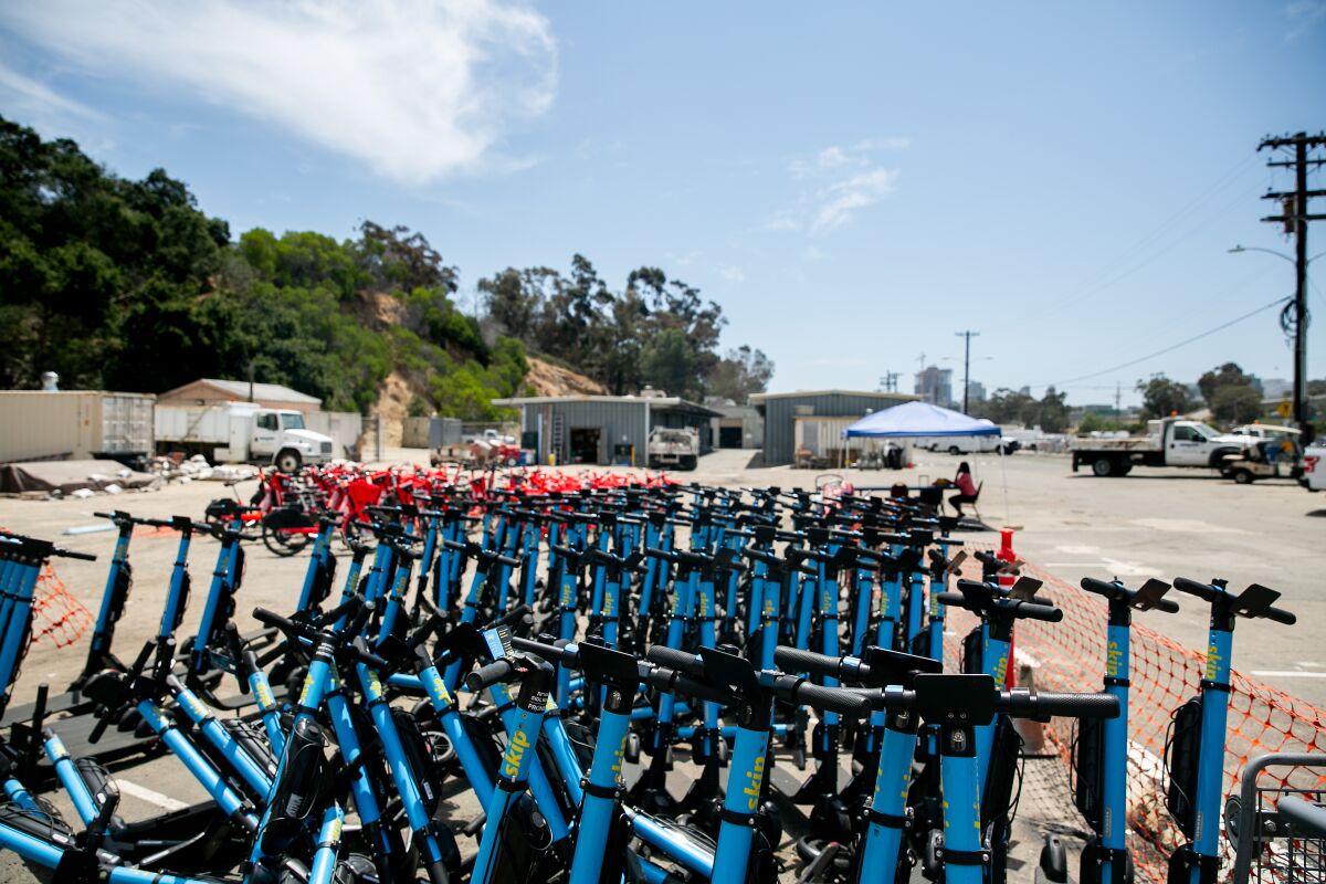 Rows of Skip scooters and Uber's JUMP bikes that were impounded during Comic-Con sit waiting for pickup at a San Diego city facility's lot on July 24.