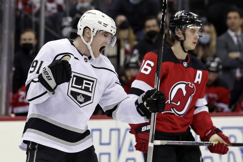 Los Angeles Kings right wing Carl Grundstrom (91) reacts to scoring a goal in front of New Jersey Devils left wing Jimmy Vesey during the third period of an NHL hockey game Sunday, Jan. 23, 2022, in Newark, N.J. The Kings won 3-2. (AP Photo/Adam Hunger)