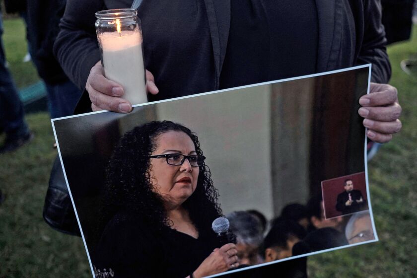 A person holds a candle with a photo of Lourdes Maldonado.