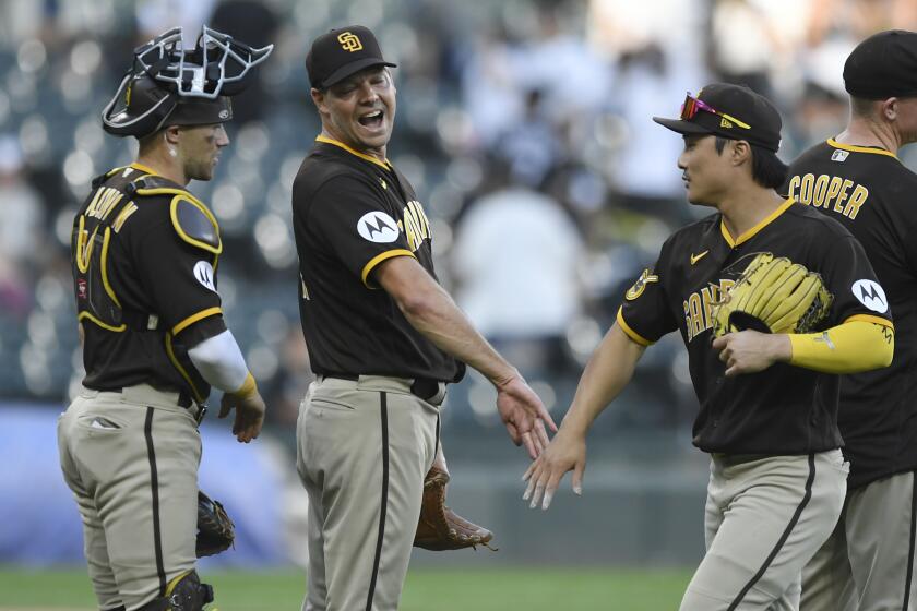 San Diego Padres closing pitcher Rich Hill, center, celebrates with catcher Brett Sulllivan, left, and Ha-Seong Kim, right, after defeating the Chicago White Sox in 11 innings of a baseball game Sunday, Oct. 1, 2023, in Chicago. (AP Photo/Paul Beaty)