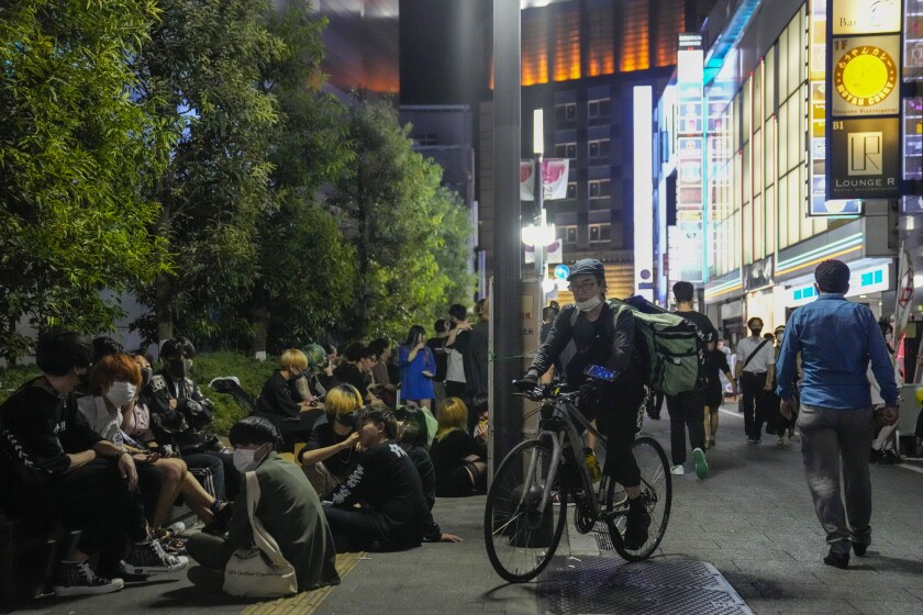 People drink on the street in Tokyo after the 8 p.m. closing time for restaurants and bars under Tokyo's state of emergency.
