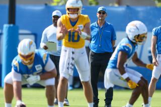 Chargers coach Jim Harbaugh stands behind quarterback Justin Herbert on the first day of training camp.