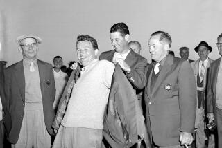 FILE - Jack Burke Jr. is helped by Cary Middlecoff as he puts on the traditional coat after winning the 20th Masters Golf Tournament at the Augusta National Golf Course in Augusta, Ga., April 8, 1956. Jack Burke Jr., the oldest living Masters champion who staged the greatest comeback ever at Augusta National for one of his two majors, died Friday morning, Jan. 19, 2024, in Houston. He was 100. (AP Photo/File)