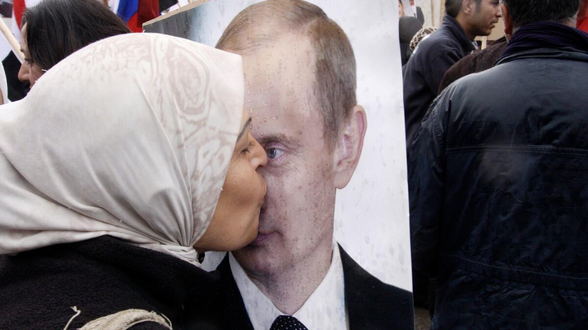 In this 2012 photo, a Syrian woman kisses a poster of Russian President Vladimir Putin during a pro-Syrian government demonstration in front of the Russian Embassy in Damascus, Syria.