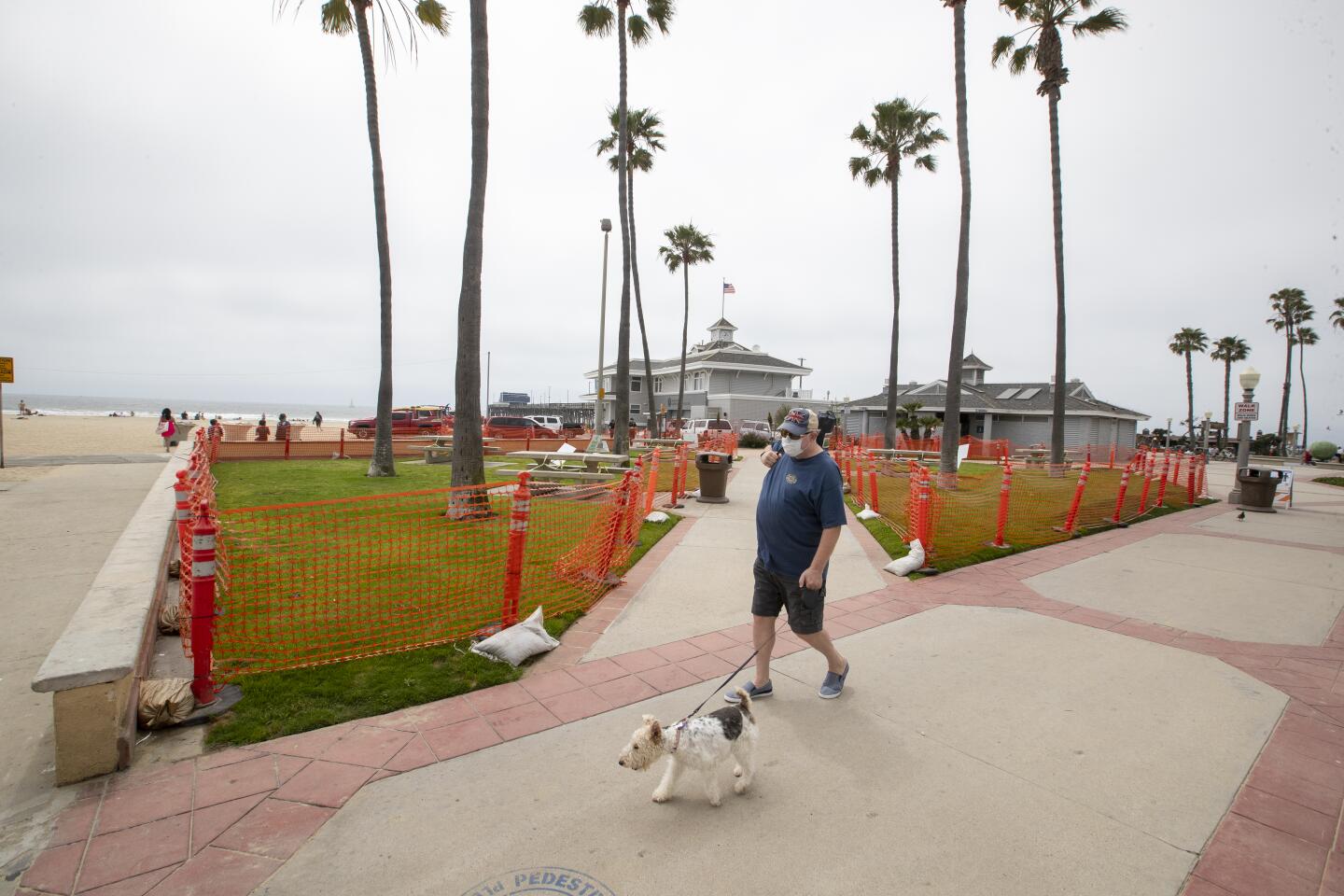 A man walks his dog past a closed park in Newport Beach