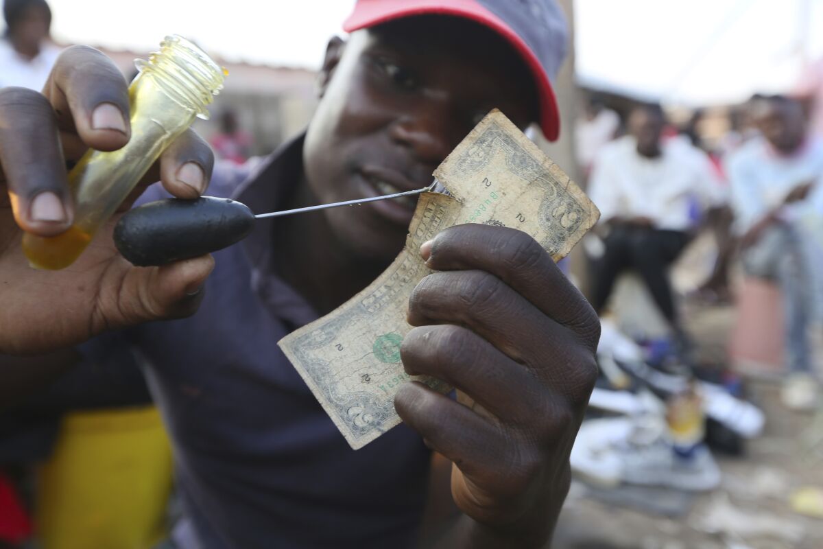 A currency trader mends a worn $2 bill at a market in Harare, the capital of Zimbabwe.