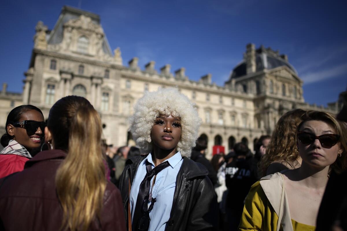 Fashion lovers wait in the courtyard of the Louvre museum during Louis Vuitton ready-to-wear Spring/Summer 2023 fashion collection presented Tuesday, Oct. 4, 2022 in Paris. (AP Photo/Christophe Ena)