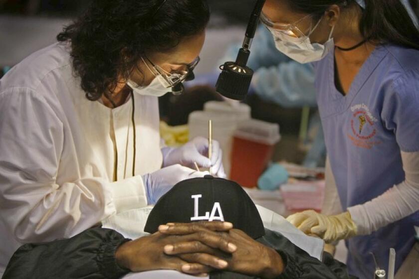 A volunteer dentist and assistant perform dental work at last August's free clinic.