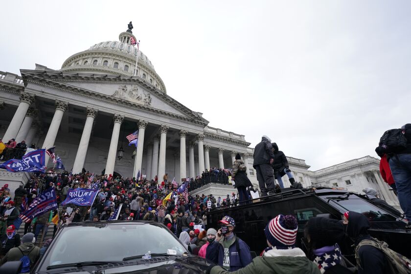 Trump supporters stand on top of a police vehicle, Wednesday, Jan. 6, 2021, at the Capitol in Washington. As Congress prepares to affirm President-elect Joe Biden's victory, thousands of people have gathered to show their support for President Donald Trump and his claims of election fraud. (AP Photo/Julio Cortez)