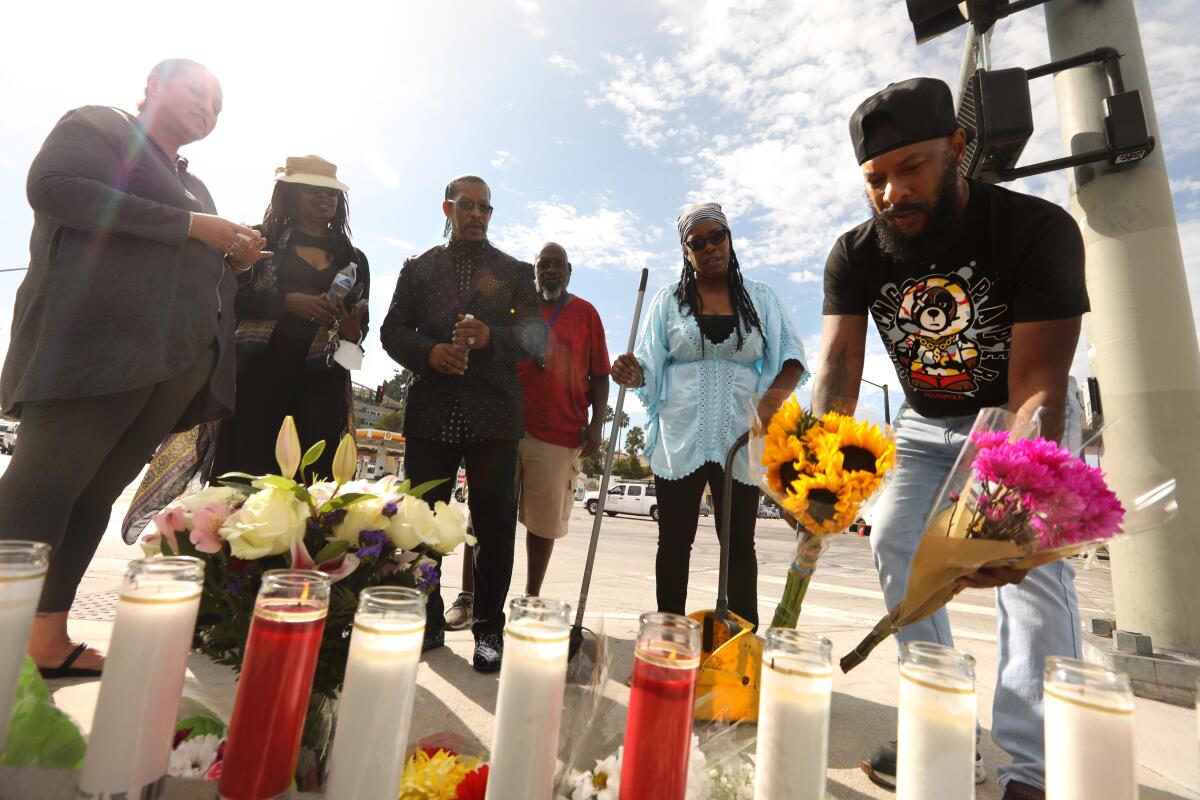 Terrell Simon, right, leaves flowers at a memorial across the street from a fiery crash in Windsor Hills 